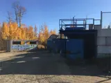 Blue garbage bins with trees and pesticide recycling building